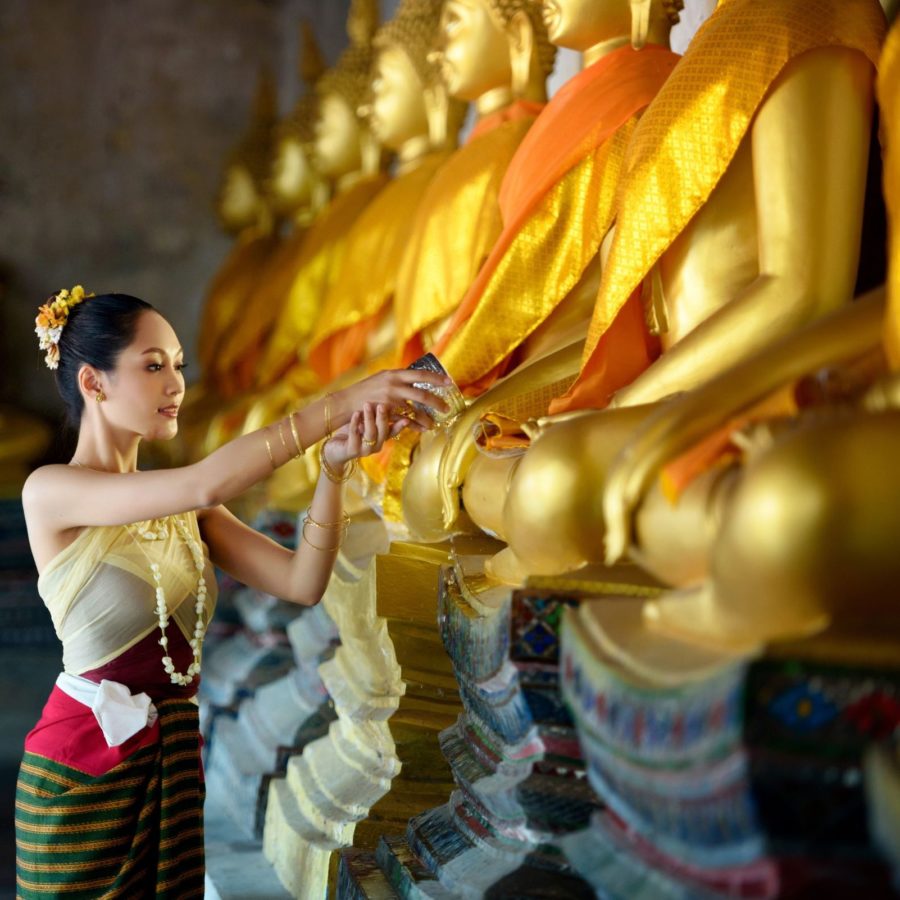 Frau bewässert Buddha am Neujahrsfest, Laos